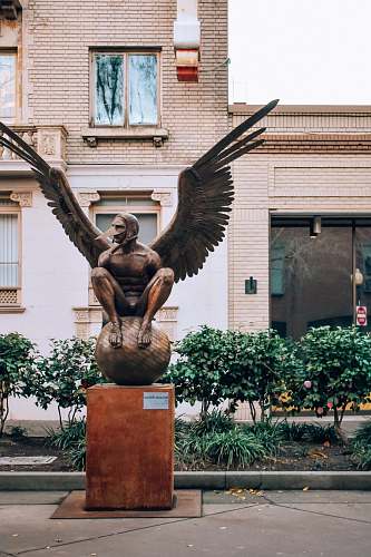 sculpture brown concrete statue of man holding book statue