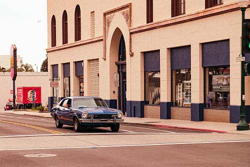 car black sedan parked beside brown concrete building during daytime transportation