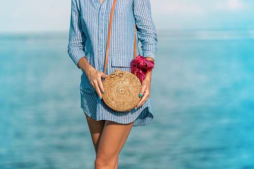 purse woman wearing blue and white striped dress shirt dress with brown wicker crossbody bag near sea at daytime los angeles