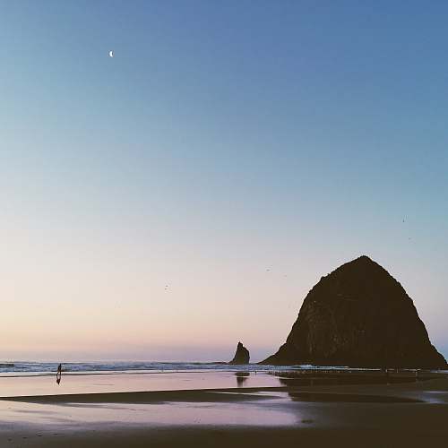 ocean photo of person on seashore far away from islet sea