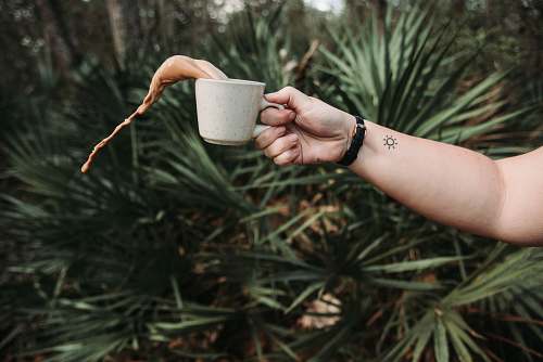 cup person holding white ceramic teacup spilling coffee coffee cup