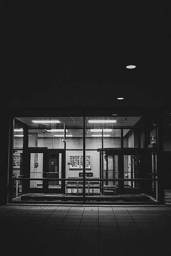 lighting grayscale photo of glass window corridor