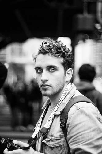 person grayscale photo of man holding camera human
