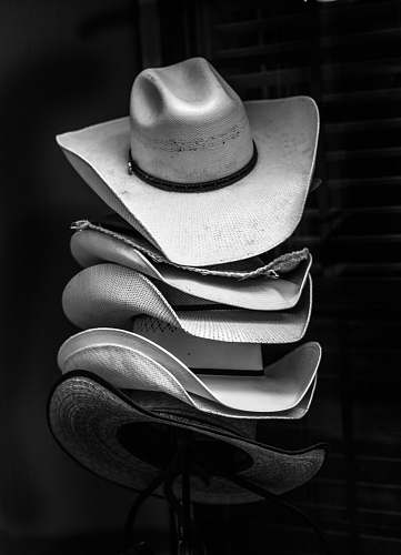 hat grayscale photography of piled cowboy hats clothing
