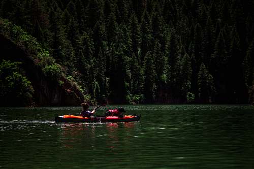 canoe person riding kayak on body of water rowboat