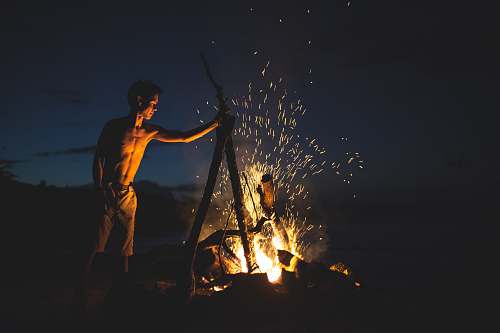 campfire topless man lighting bonfire fire