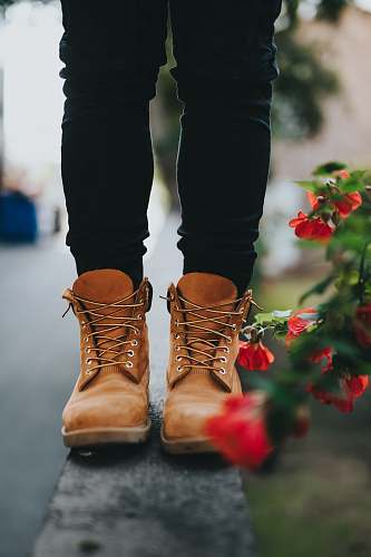 clothing person wearing pair of brown boots near flowers footwear