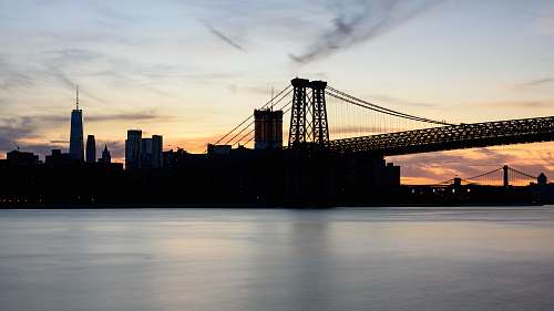 building silhouette photograph of bridge and city buildings sunrise