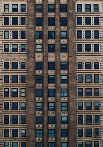 city brown concrete building with blue glass windows during daytime brick