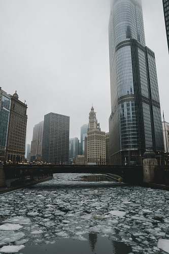 architecture frozen river under bridge photo during foggy daytime skyscraper