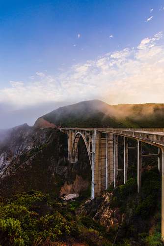 bridge gray concrete bridge over green mountains during daytime architecture