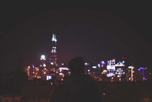 human man in black hoodie standing near city buildings during night time person