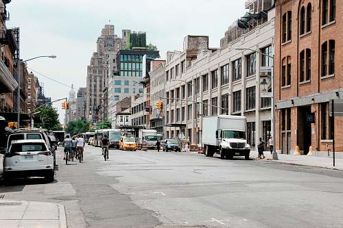 road people walking and riding bike in front of high-rise buildings during daytime street