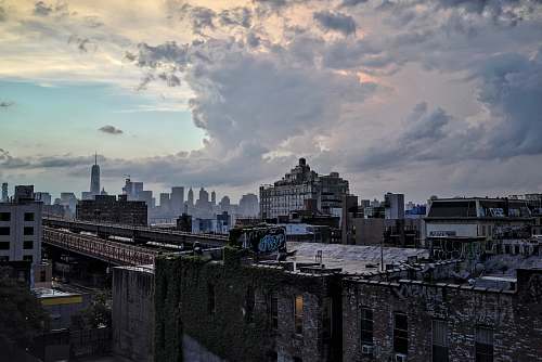 city photo of black concrete building under white clouds at noontime urban