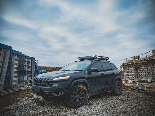 offroad black Jeep Cherokee SUV parked on gravel ground blue