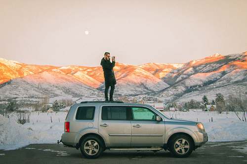 vehicle man standing on top of SUV midway