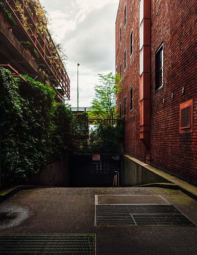 brick brown brick building near green plants during daytime urban