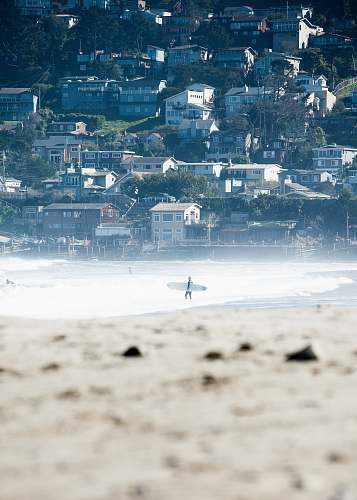 pacifica person carrying white surfboard walking on the shoreline beach