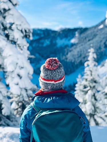 apparel person wearing gray bobble knit cap and blue jacket with backpack beanie