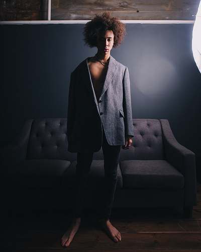 suit man standing wearing black blazer behind sofa overcoat