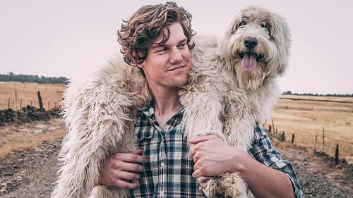 pet man carrying long-coated white dog chico