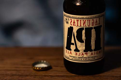 beer selective focus photography of Lagunitas IPA India Pale Ale bottle with bottle crown on tabole beverage