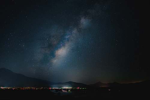 night photo of milky way under lighted high-rise buildings space