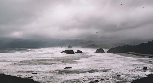 nature rock formations between sea under gray sky sea