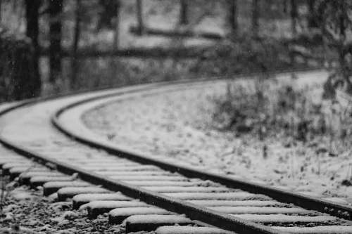 black-and-white selective focus photography of black metal railroad covered with snow railway