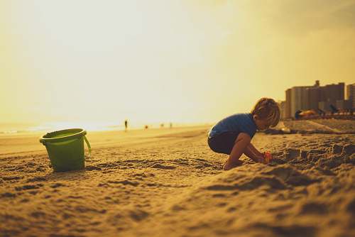people child playing on sand near pail sand