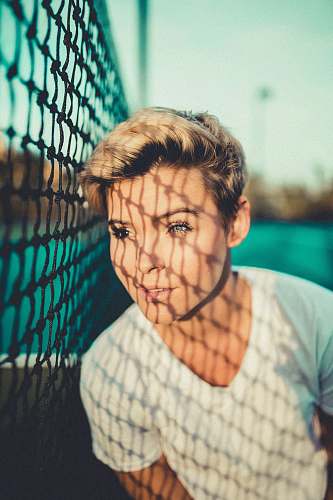 people close up photo of woman with V-neck t-shirt close to black net person
