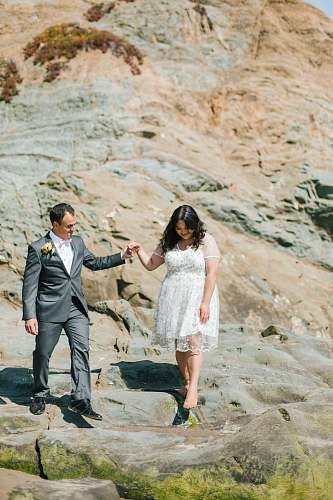 person couple walking beside rock formation suit