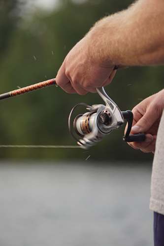 person focus photo of man holding fishing rod and fishing reel people