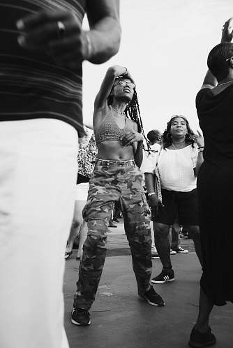 person grayscale photo of woman dancing surrounded by people black-and-white
