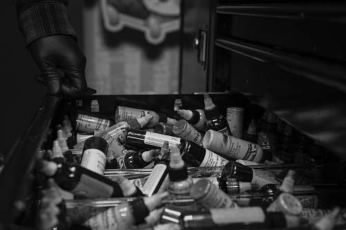 person grayscale photography of drawer full of bottles black-and-white