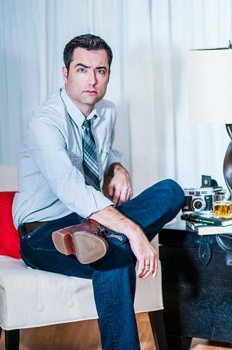 people man cross-legged sitting on padded sofa chair person
