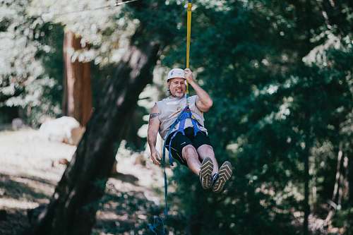 person man hanging and wearing harness during daytime apparel