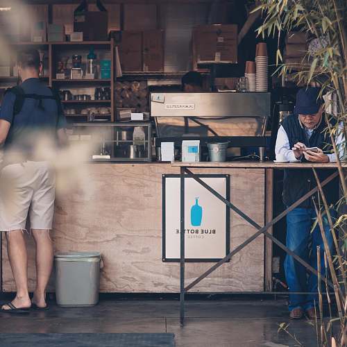 people man leaning on table in front of coffee store person