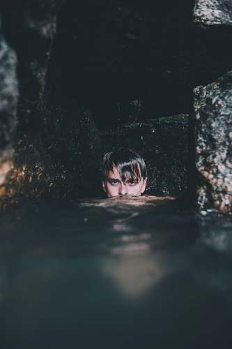 person man near rock formation soaking on water people