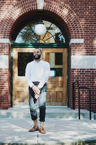 person man standing in front of brown wooden door during daytime people