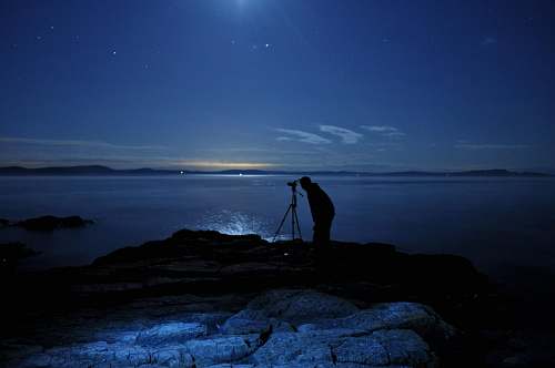 person man taking photo with camera on tripod in beach photographer
