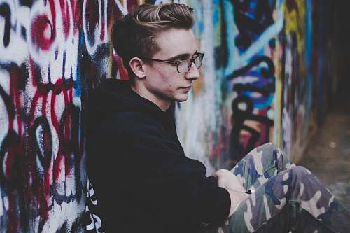 people man wearing black hoodie and leaning on wall graffiti