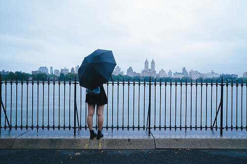 person person holding umbrella near sea railing