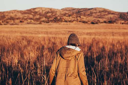 person person wearing jacket walking in brown grass field people