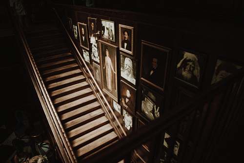 person photo frames hanged on wall beside empty brown wooden stairs people