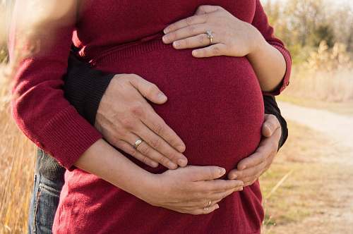 person pregnant woman standing behind the man holding tummy people