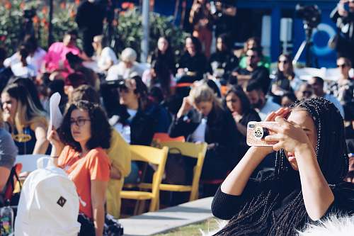 person woman holding brown smartphone crowd