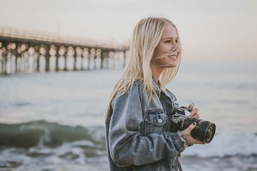 person woman holding camera standing on seashore camera