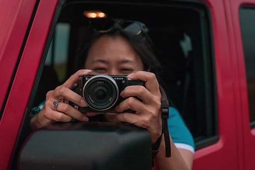 person woman holding DSLR camera in red vehicle camera