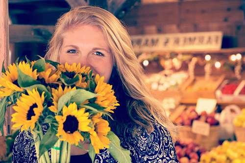 people woman in blue and white floral top holding sunflower buoquet person